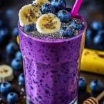 Delicious banana-blueberry smoothie in a glass with fresh fruit on the side.