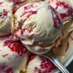 Homemade strawberry vanilla bean ice cream served in a bowl with fresh strawberries.