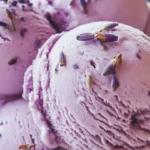 A bowl of homemade honey lavender ice cream topped with lavender flowers.