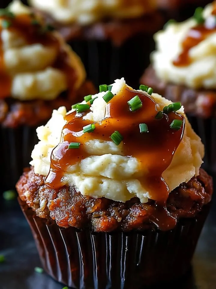 Meatloaf cupcakes topped with whipped potato frosting on a white plate.