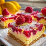Raspberry Lemon Cheesecake Bars topped with fresh raspberries on a white plate