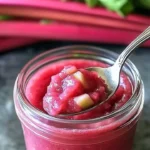 Jar of homemade rhubarb butter spread on toast with fresh rhubarb stalks