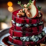 Elegant roasted beet and blue cheese towers appetizer on a white plate.