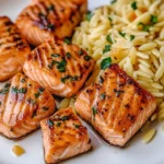 Delicious salmon bites served with lemon butter orzo on a plate