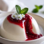 White Burrata Panna Cotta topped with liquid raspberry core on a plate.